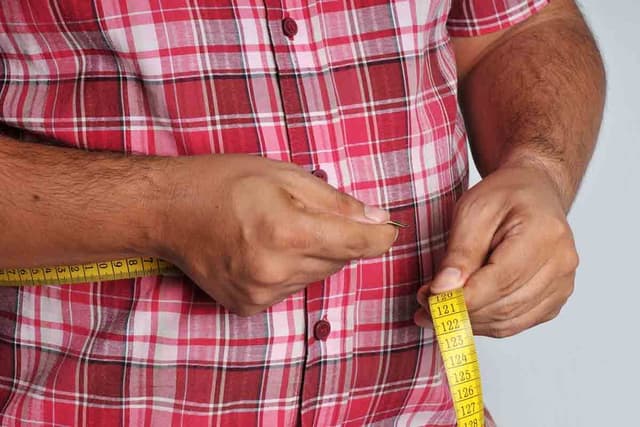 Overweight man measuring waist